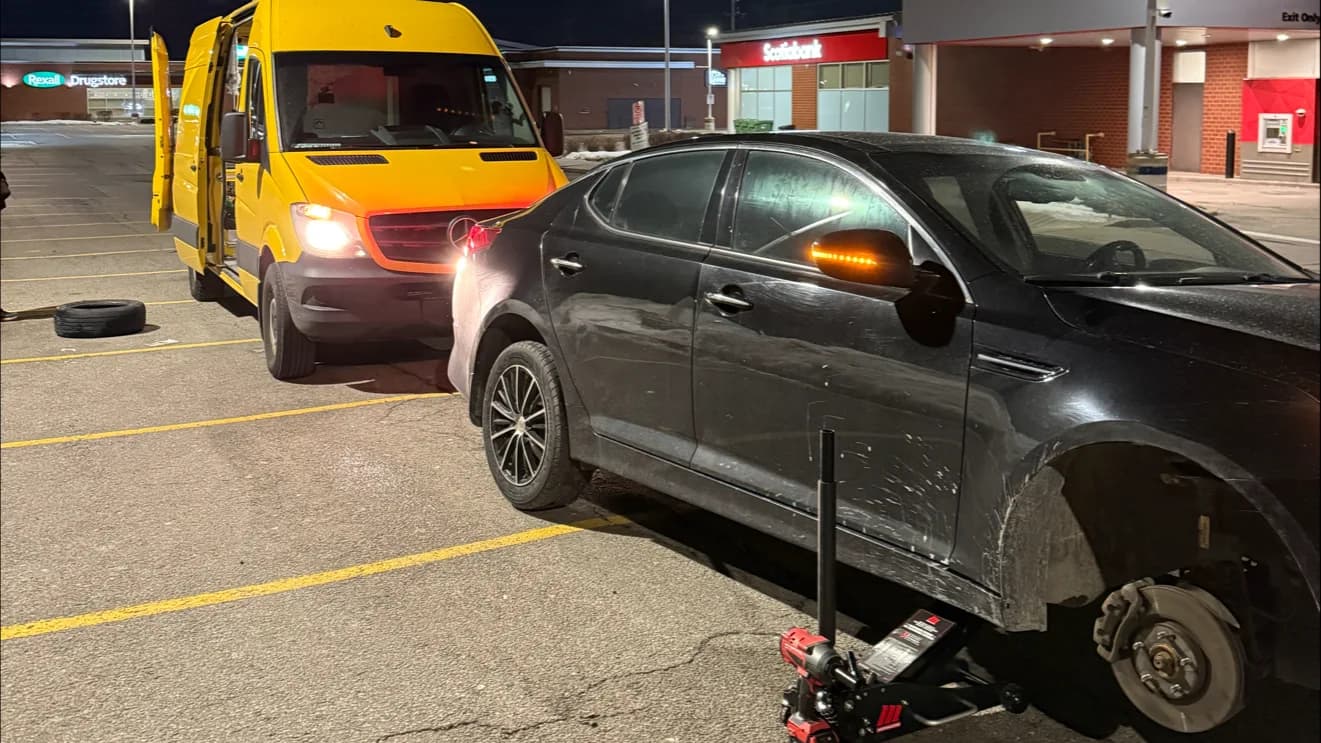 Late-night GTA roadside assistance: a sedan up on the jack with the GoldenNorth van's headlights lighting the work