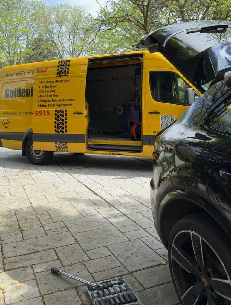 GoldenNorth van in a residential driveway with the side door open, technician helping at a black SUV